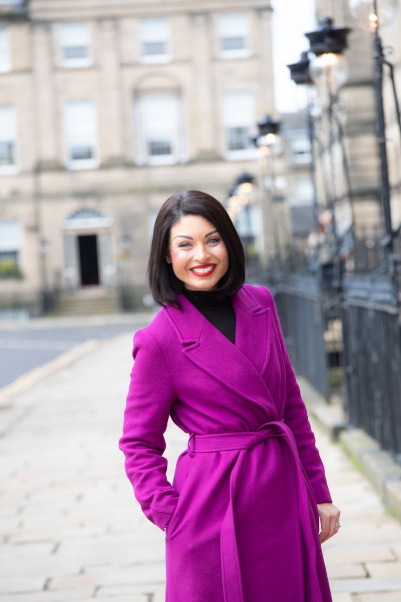 Business owner in a magenta coat on an Edinburgh street