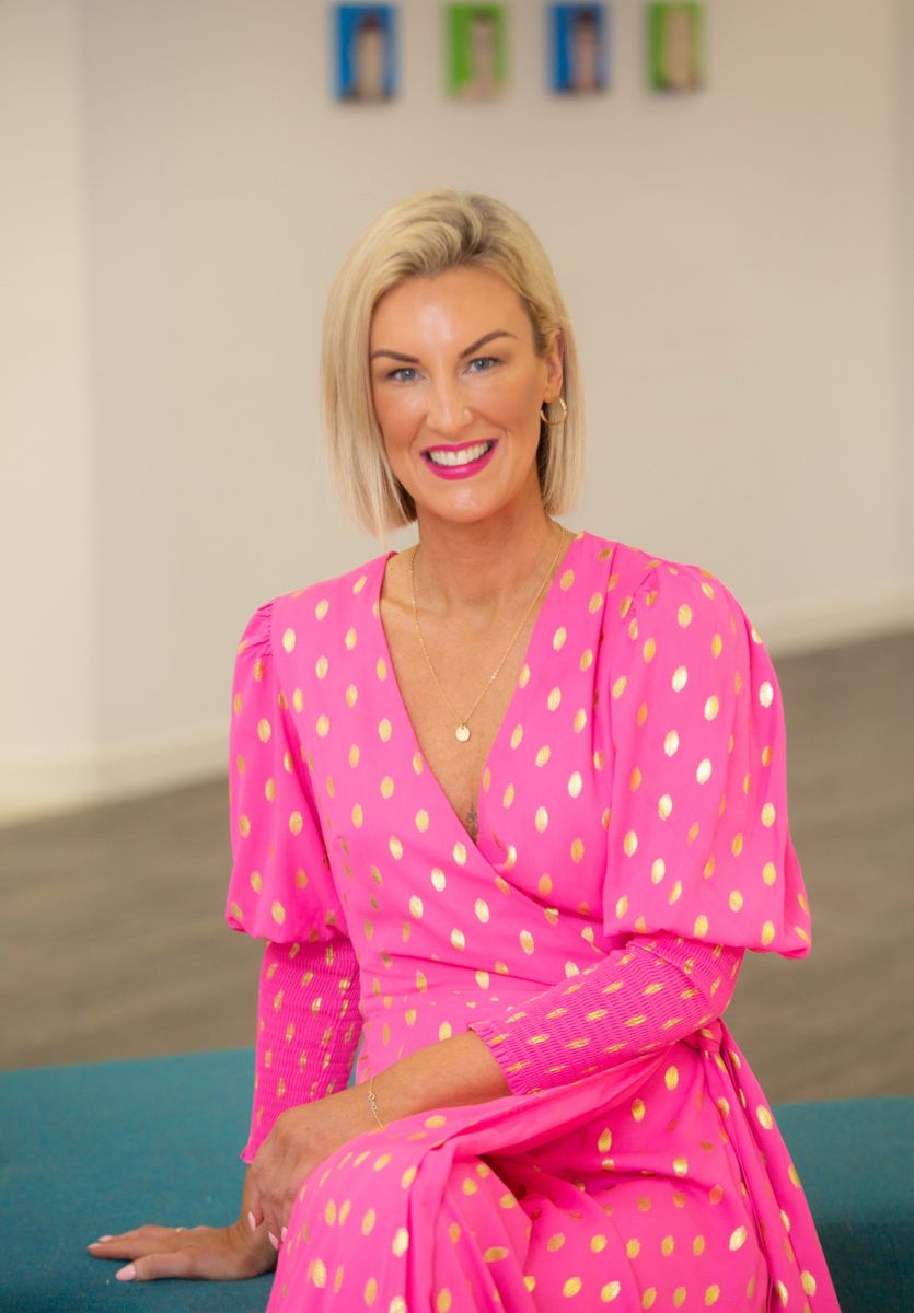 Business owner in a pink spotted dress, seated and smiling